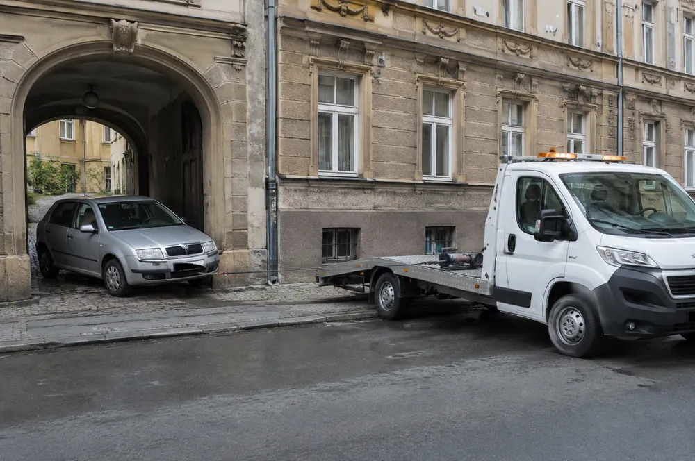 Stará Škoda Fabia vyjíždí z průjezdu činžovního domu na Smíchově k odtahovce, která čeká v ulici